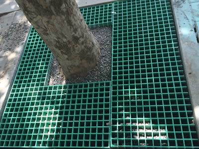 The picture shows that several pieces of molded FRP gratings are connected by clips around one tree.