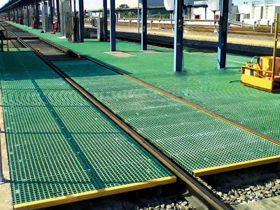 It shows green molded fiberglass gratings installed in the railway system.