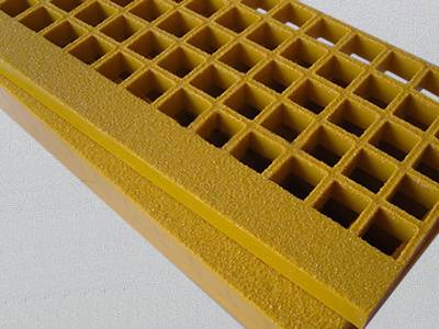 It shows two pieces of yellow fiberglass stair treads, with square meshes and heavy reinforced nosing.