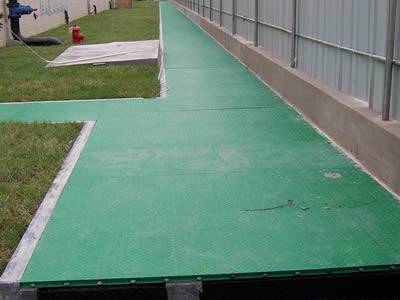 There are several pieces of green covered FRP gratings that placed above the ground.