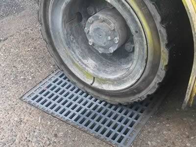 One piece of heavy duty fiberglass grating is installed above the drainage hole and one fork truck wheel is on it.