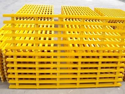 It shows several piles of pultruded fiberglass gratings in yellow, they have corrugated surface.